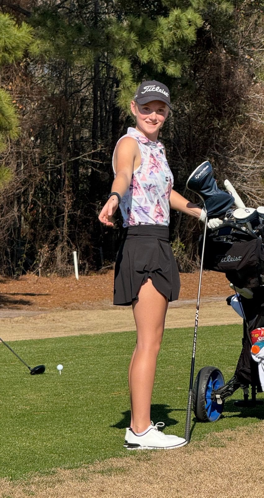 Sofie standing on the tee box next to her golf bag.