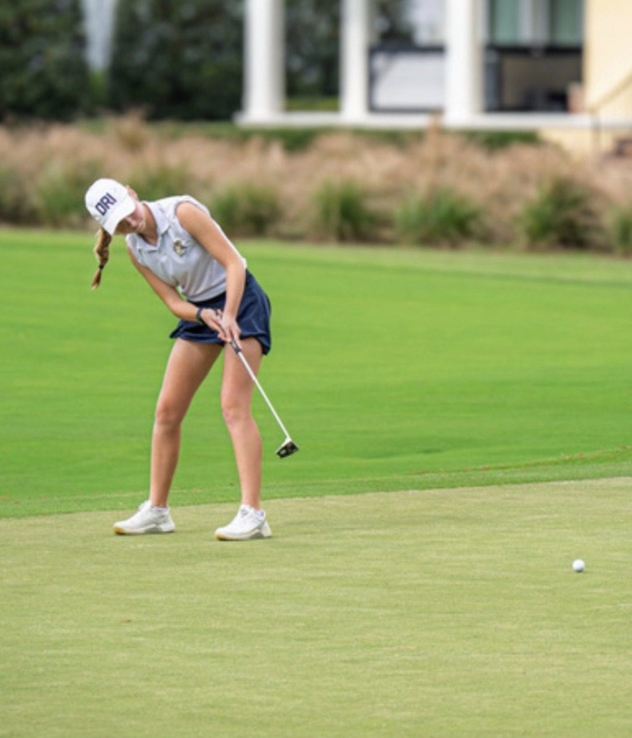 Sofie mid-putting-stroke on the practice green.