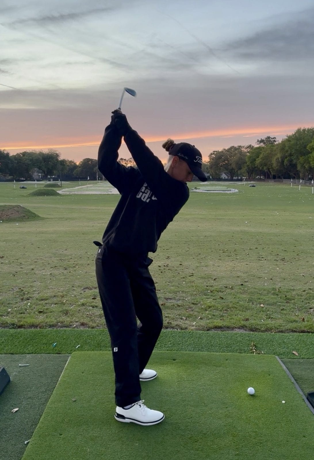 Sofie mid-backswing on the driving range.