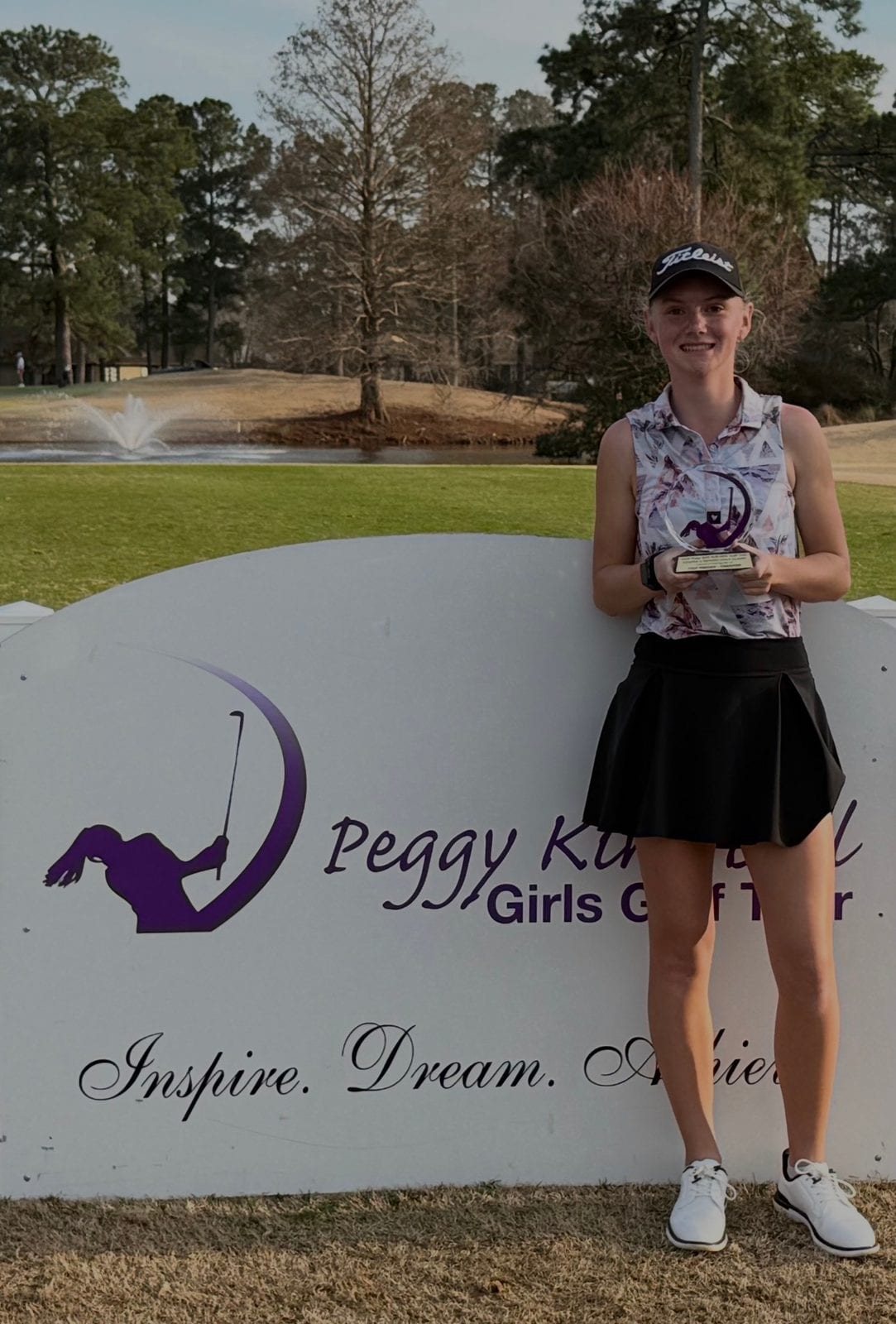Sofie smiling while holding a golf tournament trophy.