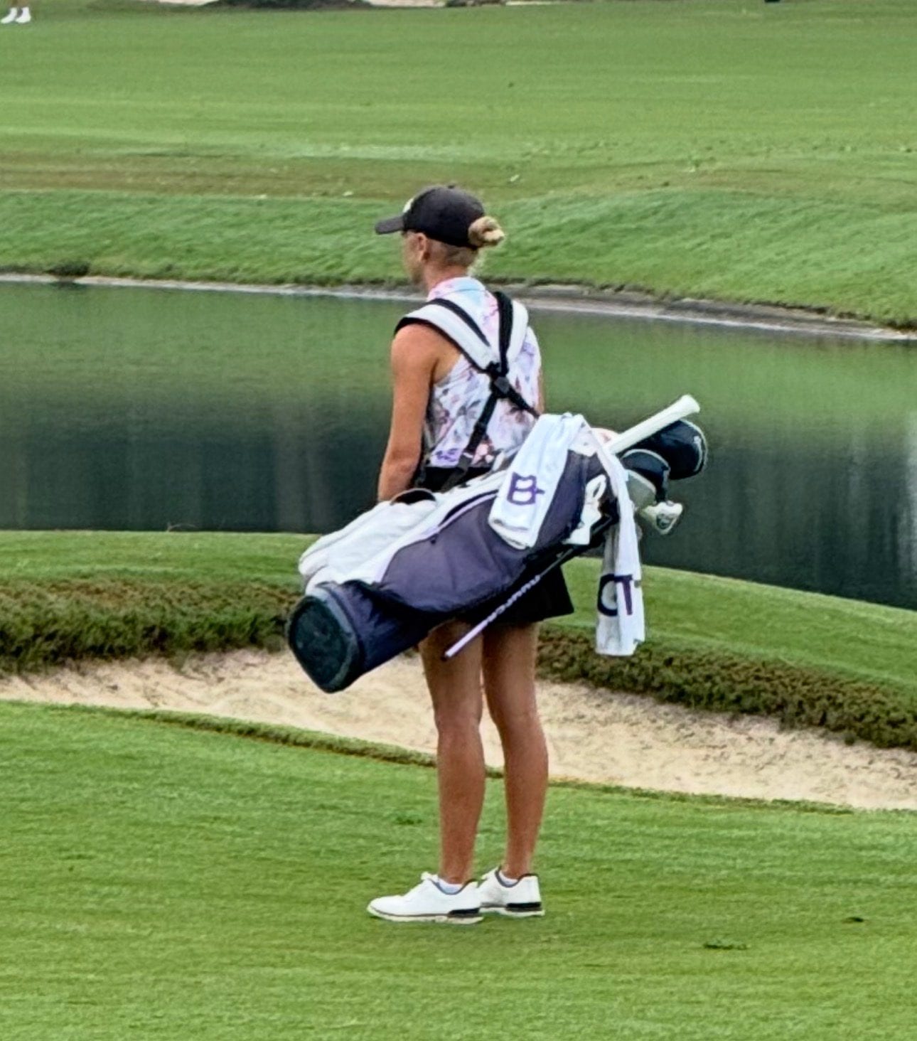 Sofie walking down the fairway with her golf bag.